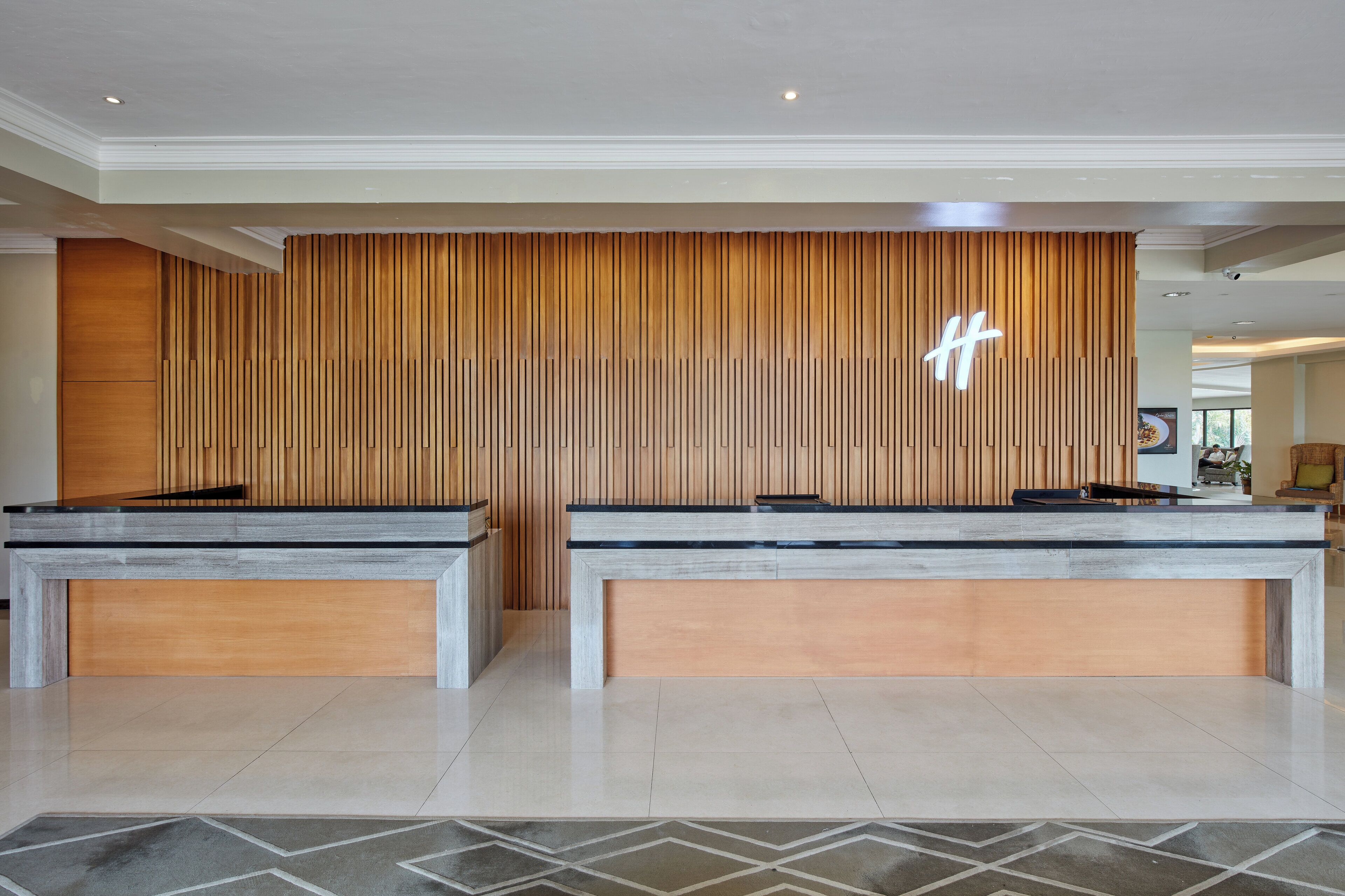 A reception area with two reception desks, a wooden panel wall, and a geometric patterned floor.