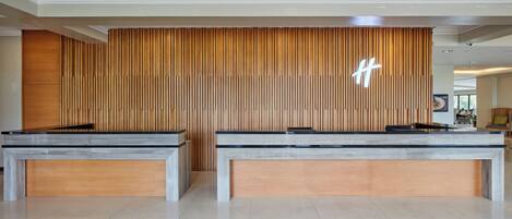 A reception area with two reception desks, a wooden panel wall, and a geometric patterned floor.