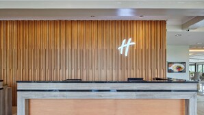 A reception desk with a wooden slat wall and a modern design. - Holiday Inn & Suites Batangas Limapark by IHG (Malvar)