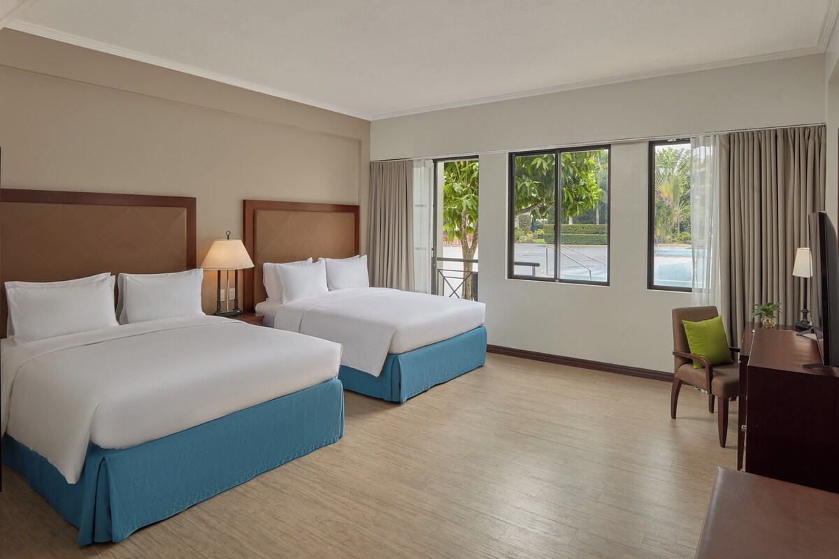 Een hotelkamer met twee bedden, een bureau, een stoel en een televisie.
