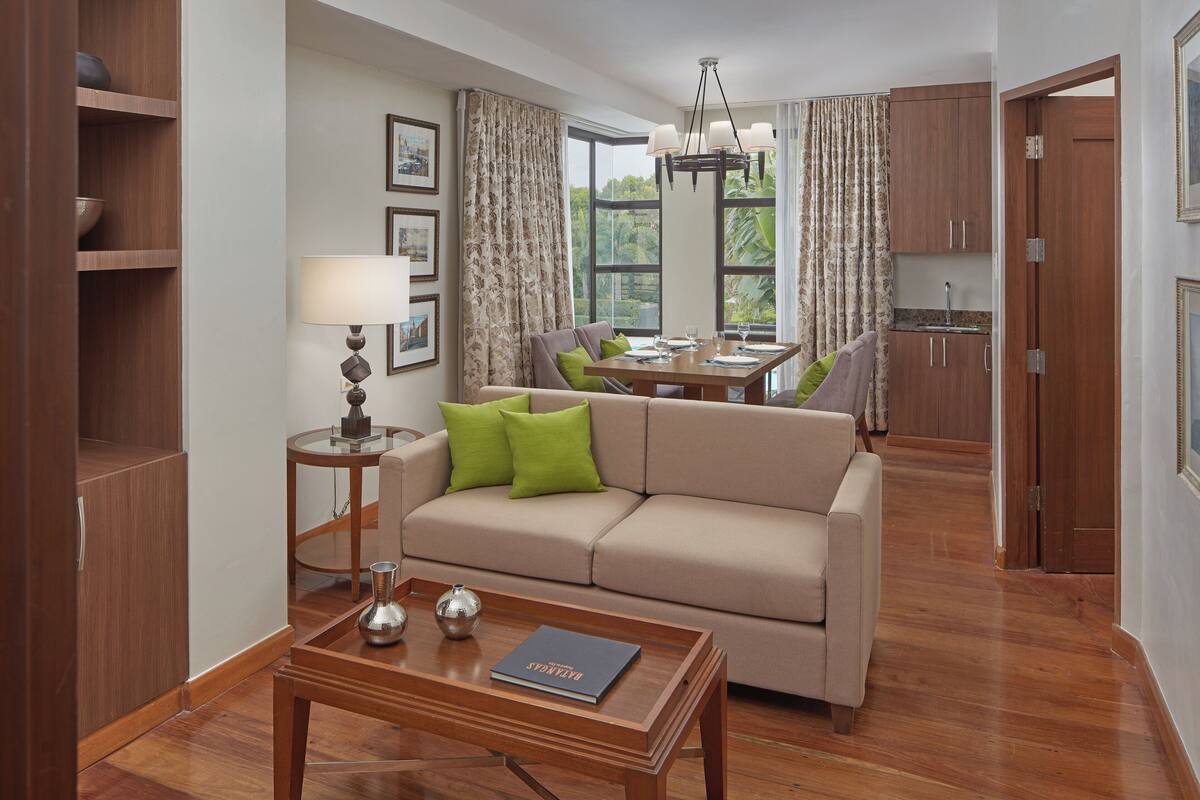 A modern living room with a sofa, a coffee table, and a dining area with a table and chairs.