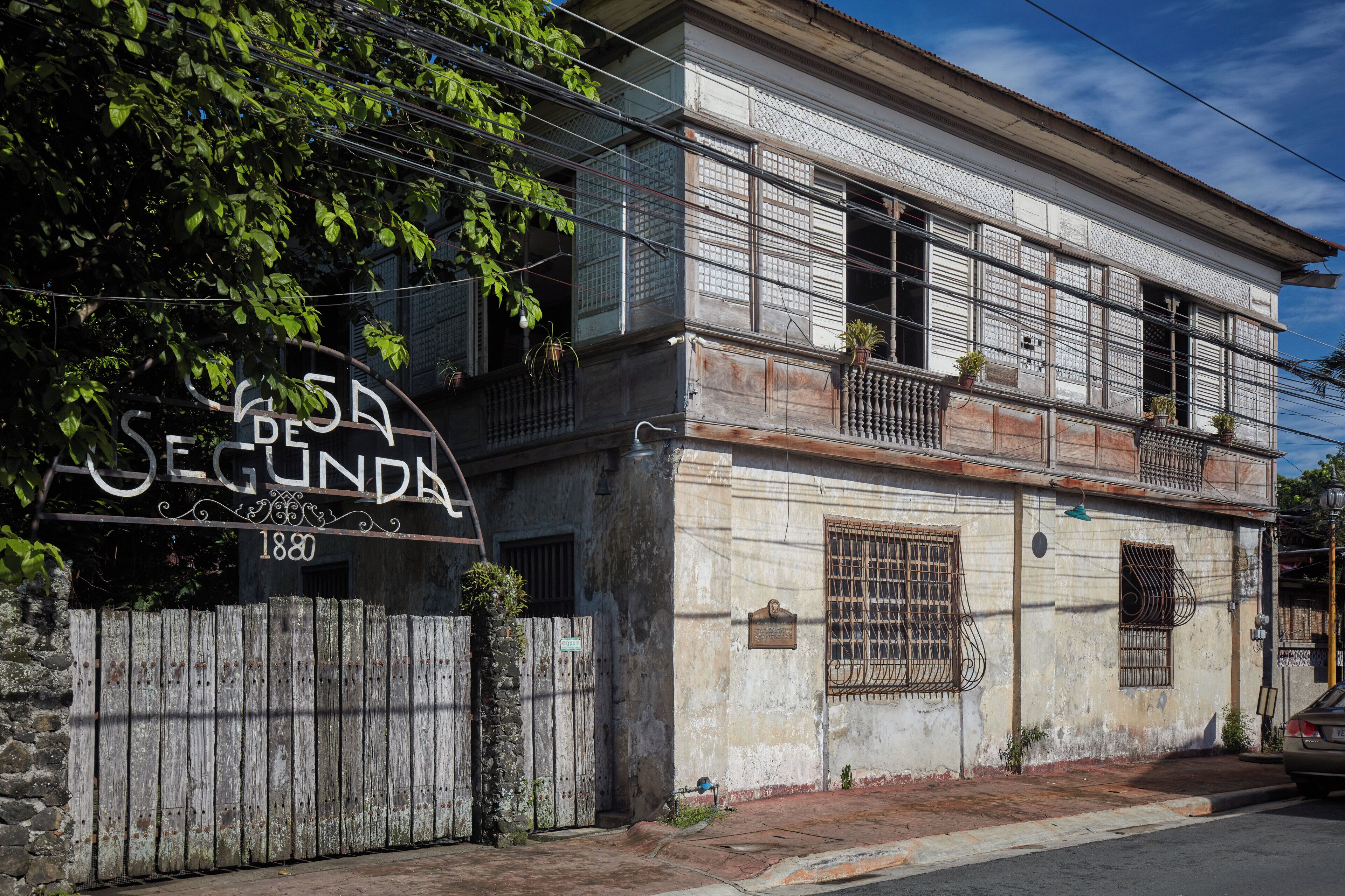A two-story building with a sign reading 'Casa de Segunda' and the year '1880' on the gate.
