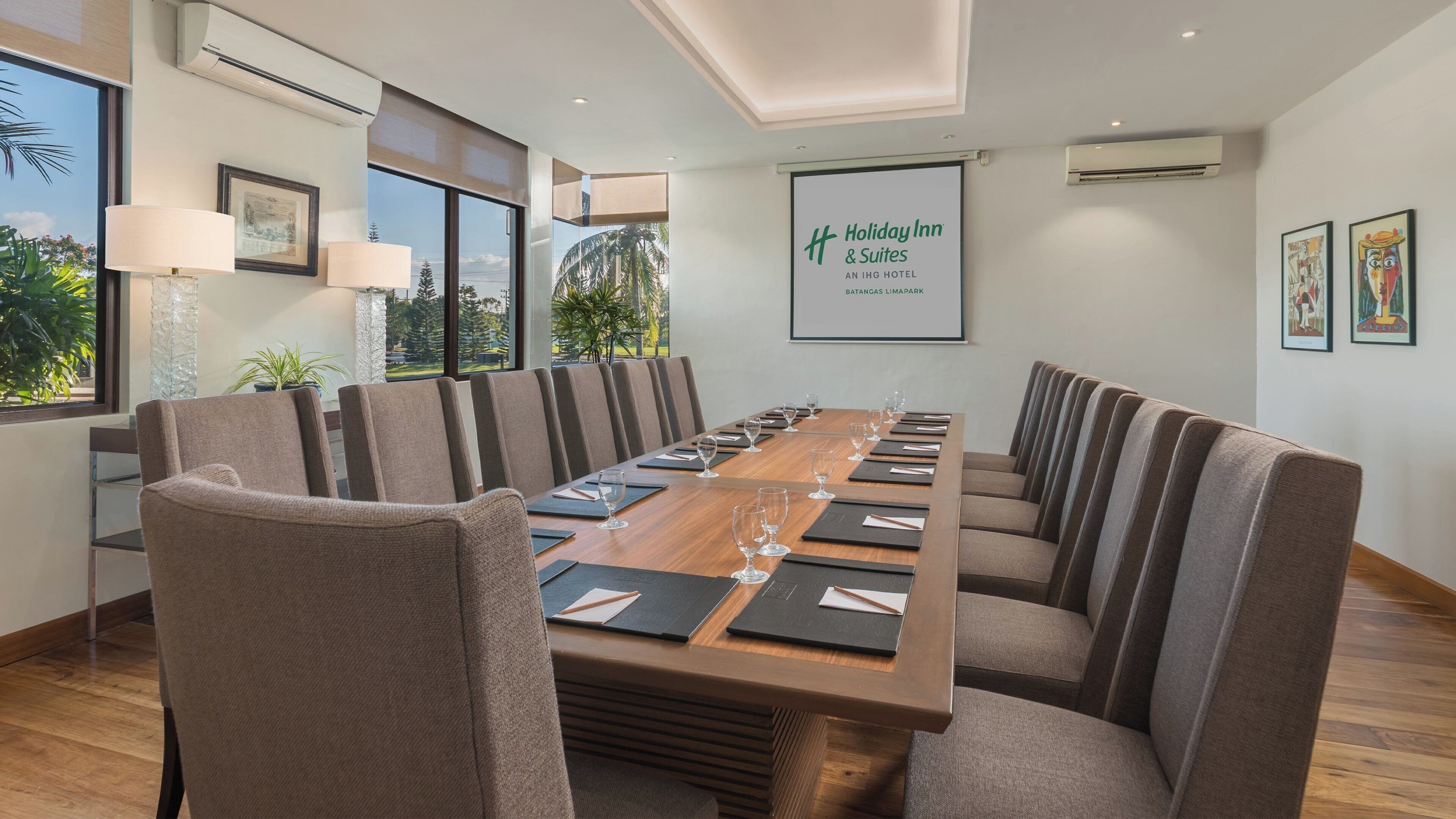 A conference room with a long table, chairs, and a framed sign.