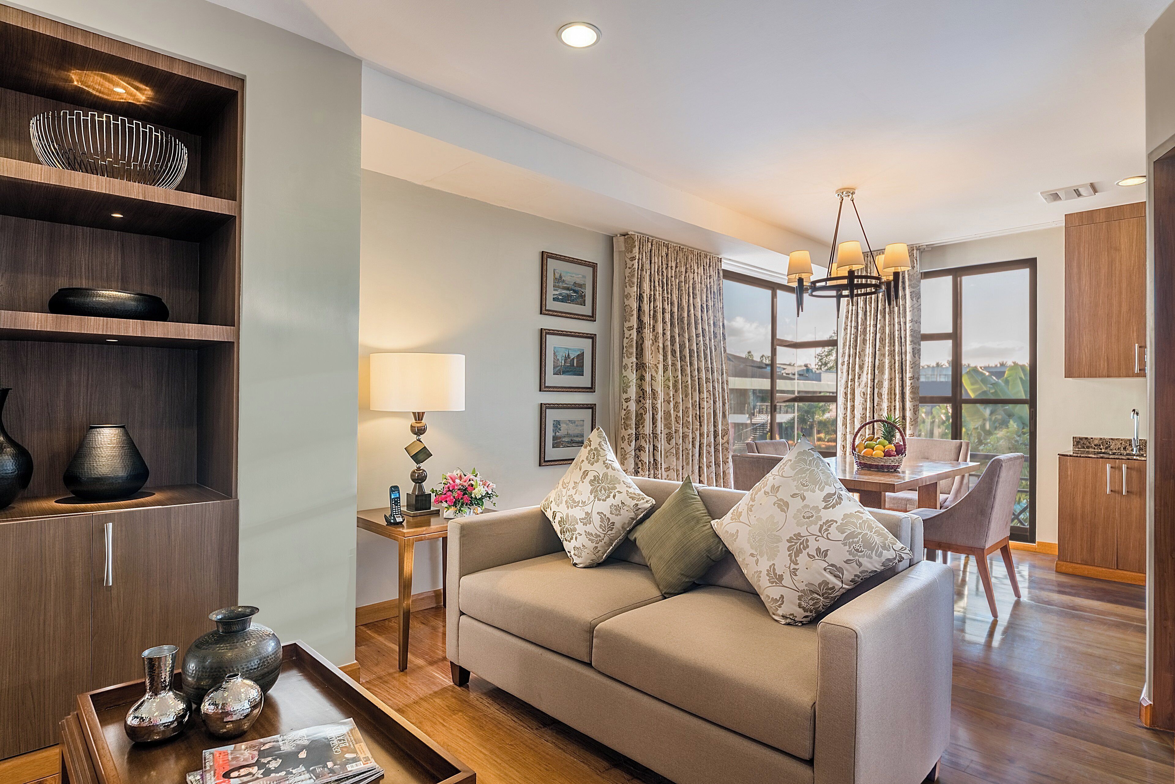 A modern living room with a sofa, a coffee table, and a dining area with a chandelier.