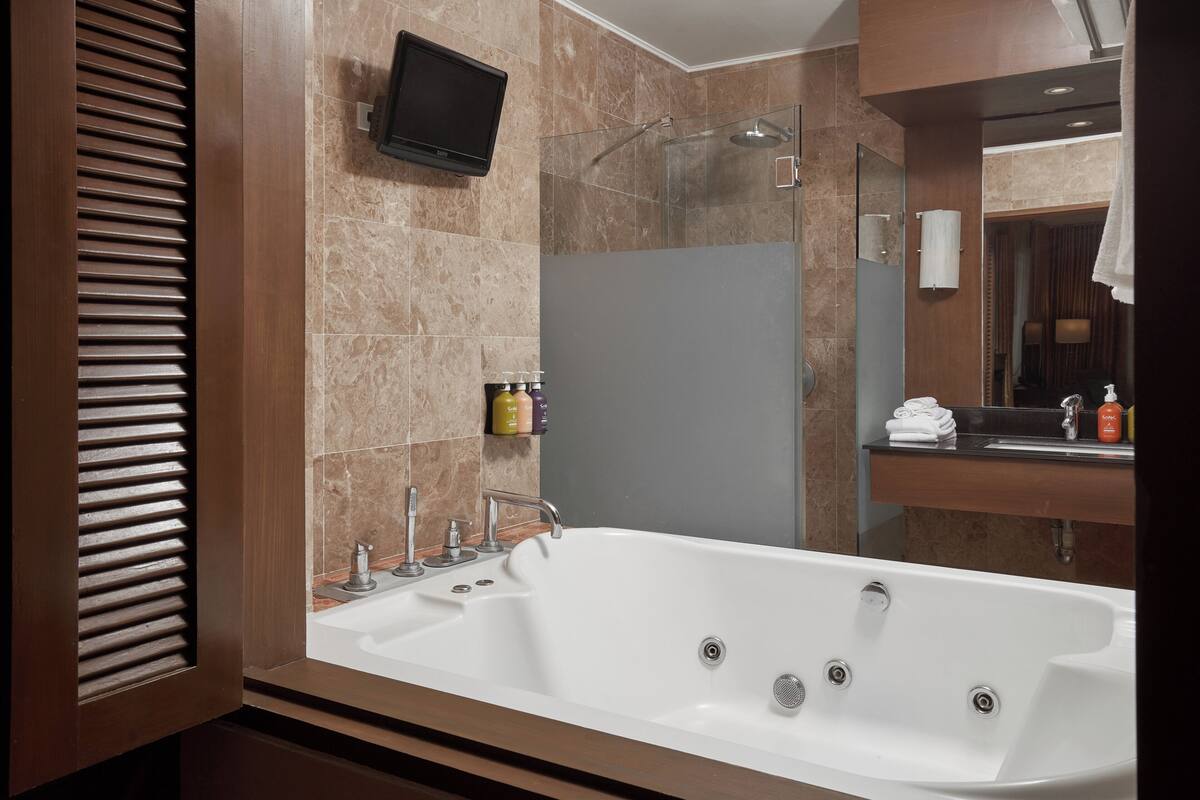 A modern bathroom with a large bathtub, a shower area, and a vanity with a mirror.