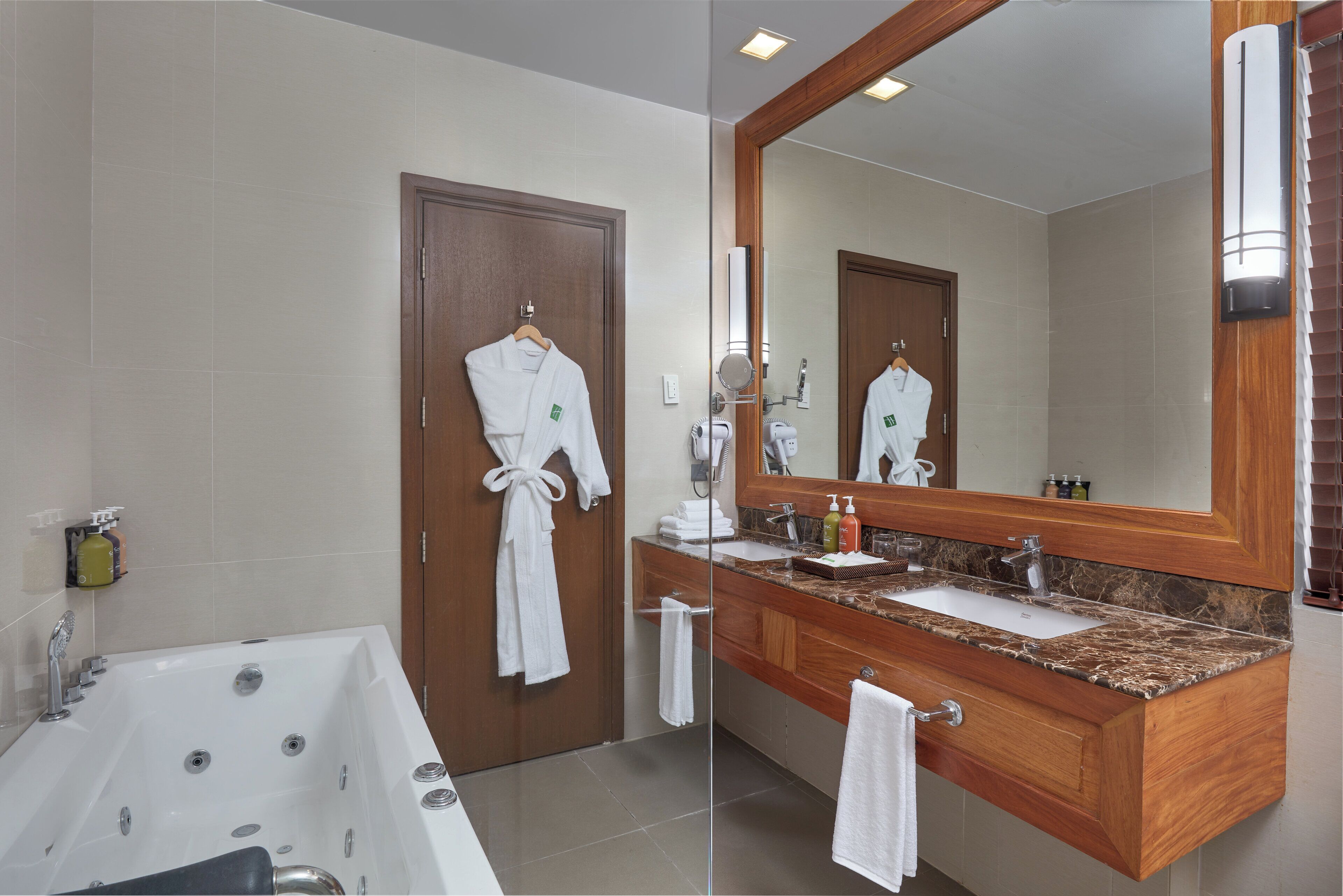 Un baño moderno con una bañera grande, tocador de madera y un espejo sobre el lavamanos.
