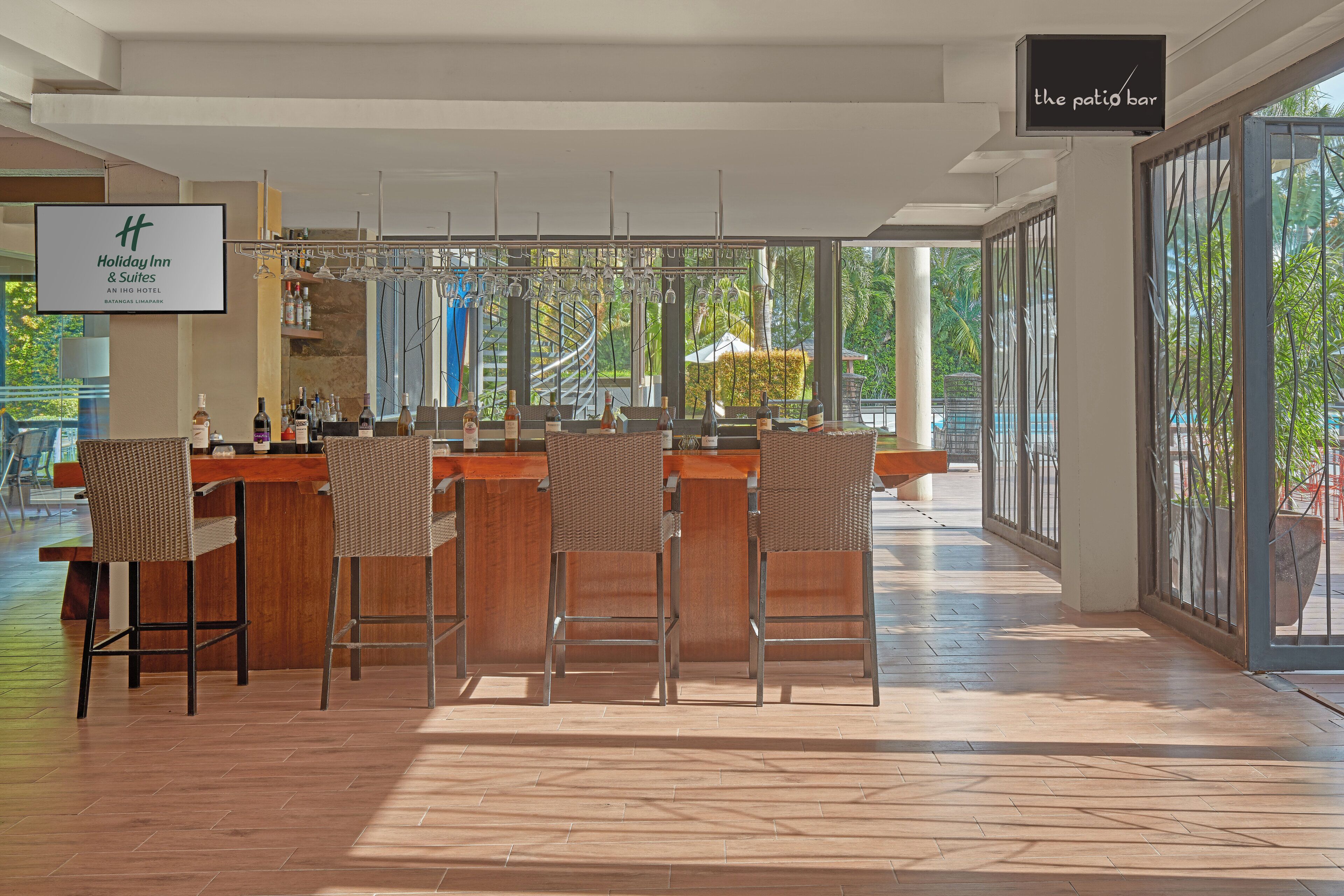 Uma área de bar com cadeiras de vime e um letreiro para 'Holiday Inn & Suites'.