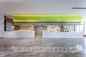A modern hotel lobby with marble flooring, a reception desk, and a bright green ceiling. - Holiday Inn Express Qidong Economic Zone by IHG (Nantong)