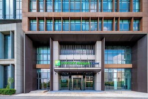 A modern hotel entrance with a glass facade, a prominent sign for Holiday Inn Express, and a set of stairs leading to the entrance. - Holiday Inn Express Qidong Economic Zone by IHG (Nantong)