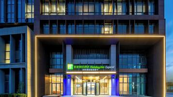 A modern hotel entrance with a revolving door, illuminated signage, and a glass facade.