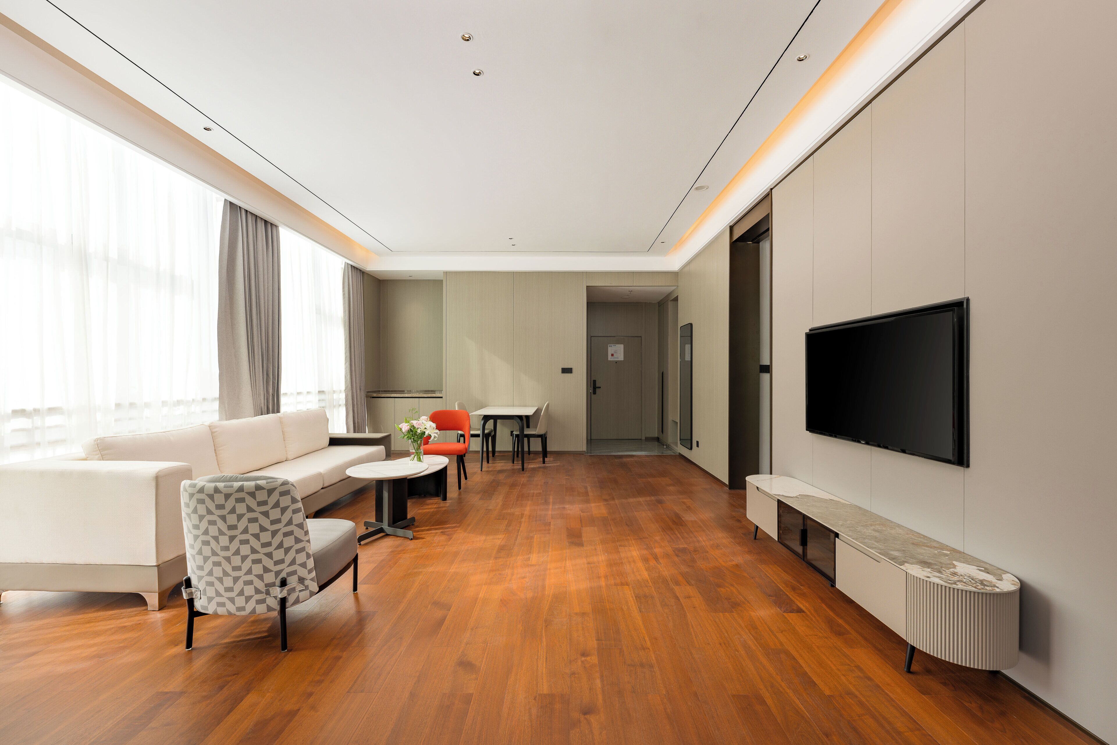 Quarto de hotel moderno com sofá, mesa de jantar, cadeiras, TV e lareira.