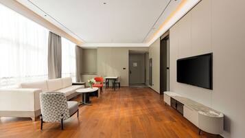 Quarto de hotel moderno com sofá, mesa de jantar, cadeiras, TV e lareira.