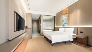 A modern hotel room with a large bed, a flat-screen TV, a bedside table, and a wall-mounted artwork. - Holiday Inn Express Qidong Economic Zone by IHG (Nantong)