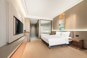Una habitación de hotel moderna con una cama grande, un televisor de pantalla plana, una mesita de noche y una obra de arte colgada en la pared.