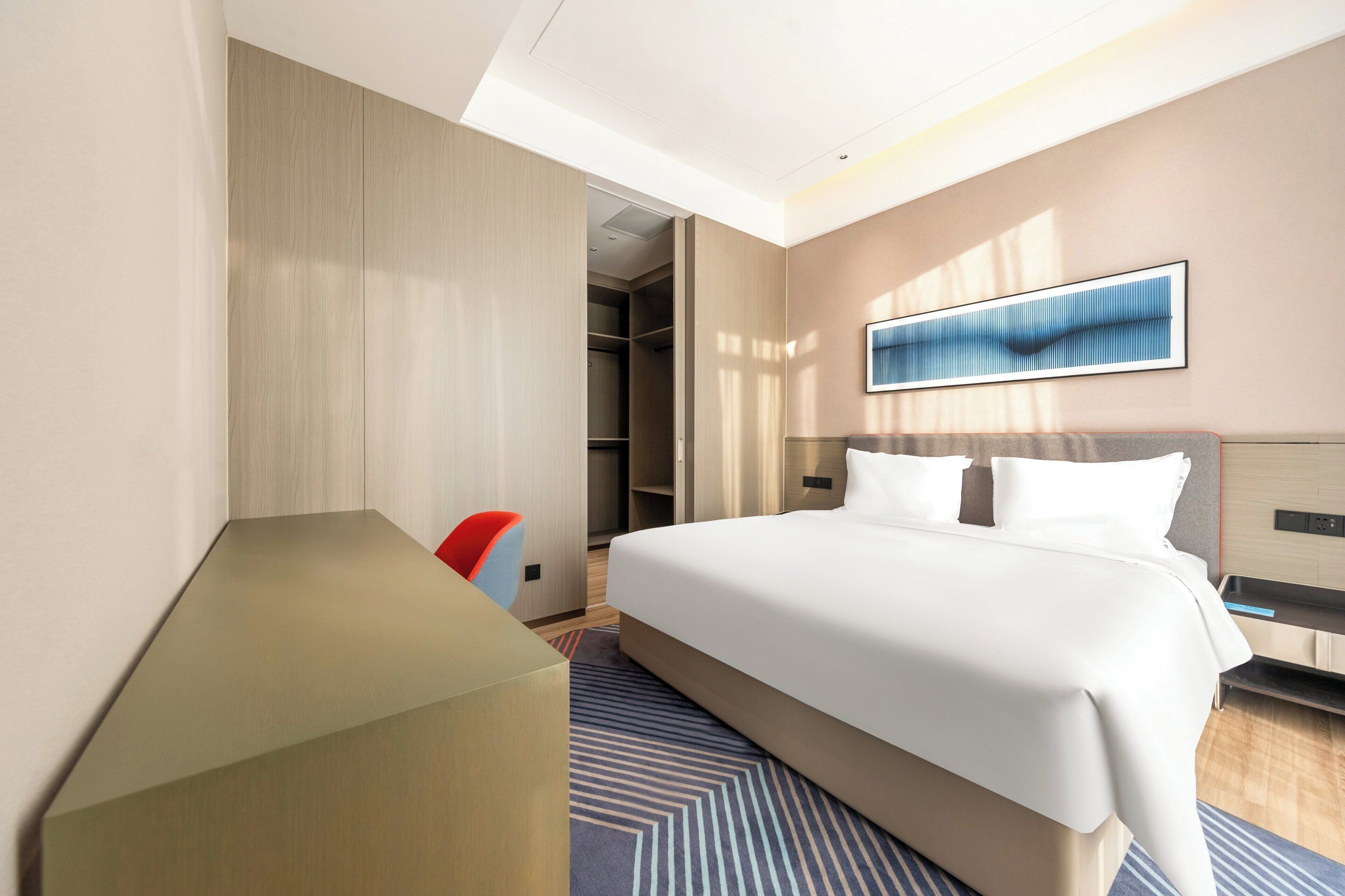 Una habitación de hotel moderna con una cama grande, un escritorio y un vestidor.