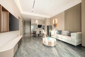 A modern living room with a sofa, a coffee table, and a TV mounted on the wall. - Holiday Inn Express Qidong Economic Zone by IHG (Nantong)
