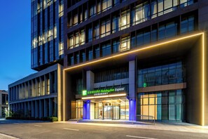 A modern hotel building with a prominent entrance, large windows, and illuminated signage. - Holiday Inn Express Qidong Economic Zone by IHG (Nantong)