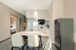A modern kitchen with a central island, a refrigerator, and a dining area with chairs. - Holiday Inn Express Qidong Economic Zone by IHG (Nantong)
