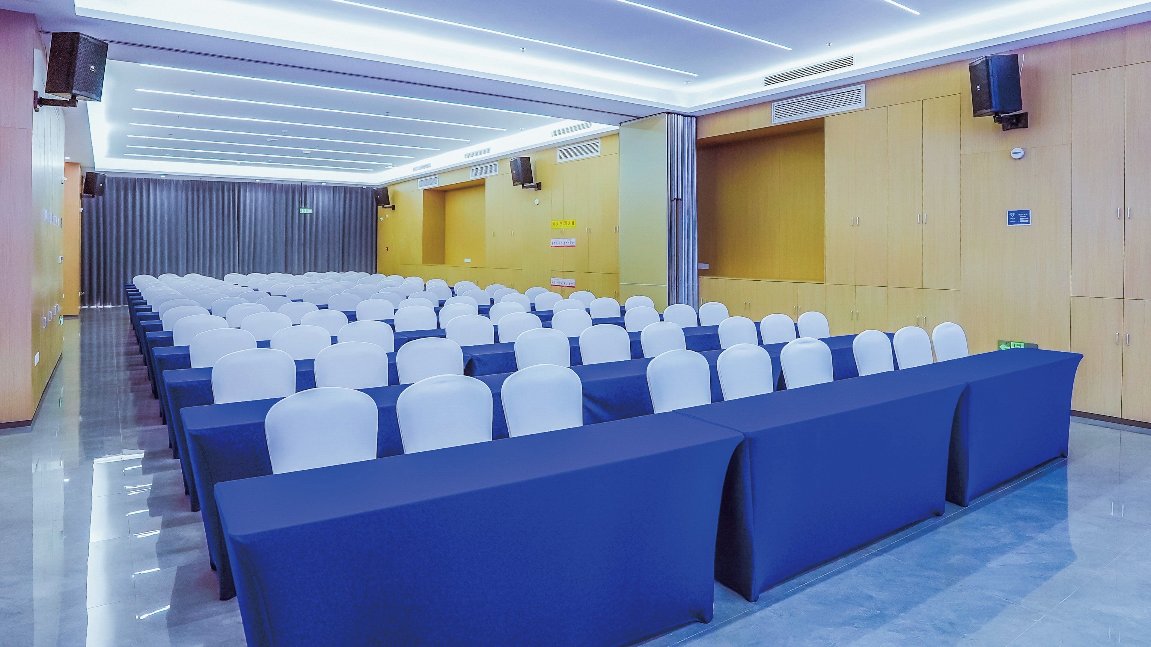 Un salón de conferencias con filas de sillas, un escenario y un atril.