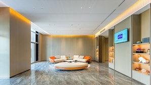 A modern lobby with a circular seating area, a flat-screen TV, and a reception desk. - Holiday Inn Express Qidong Economic Zone by IHG (Nantong)