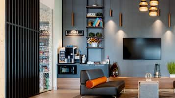 A modern living room with a flat-screen TV, a coffee machine, and a bookshelf.