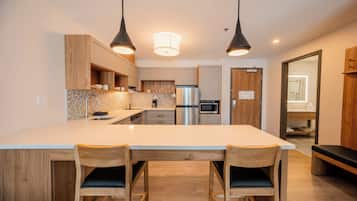 A modern kitchen with a central island, wooden cabinets, stainless steel appliances, and pendant lighting.