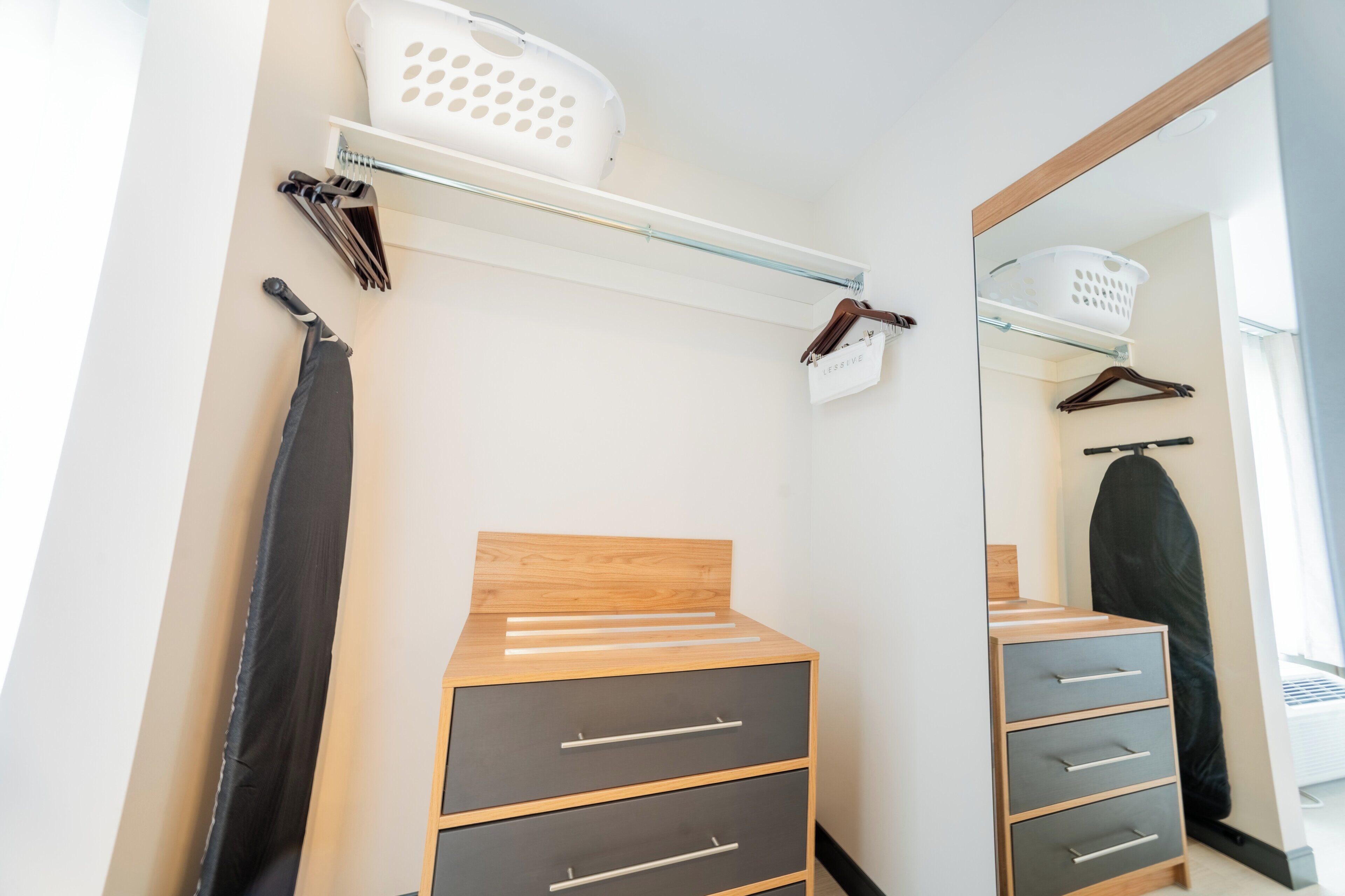 A modern bathroom with a wooden vanity, a mirror, and a hanging shower curtain.