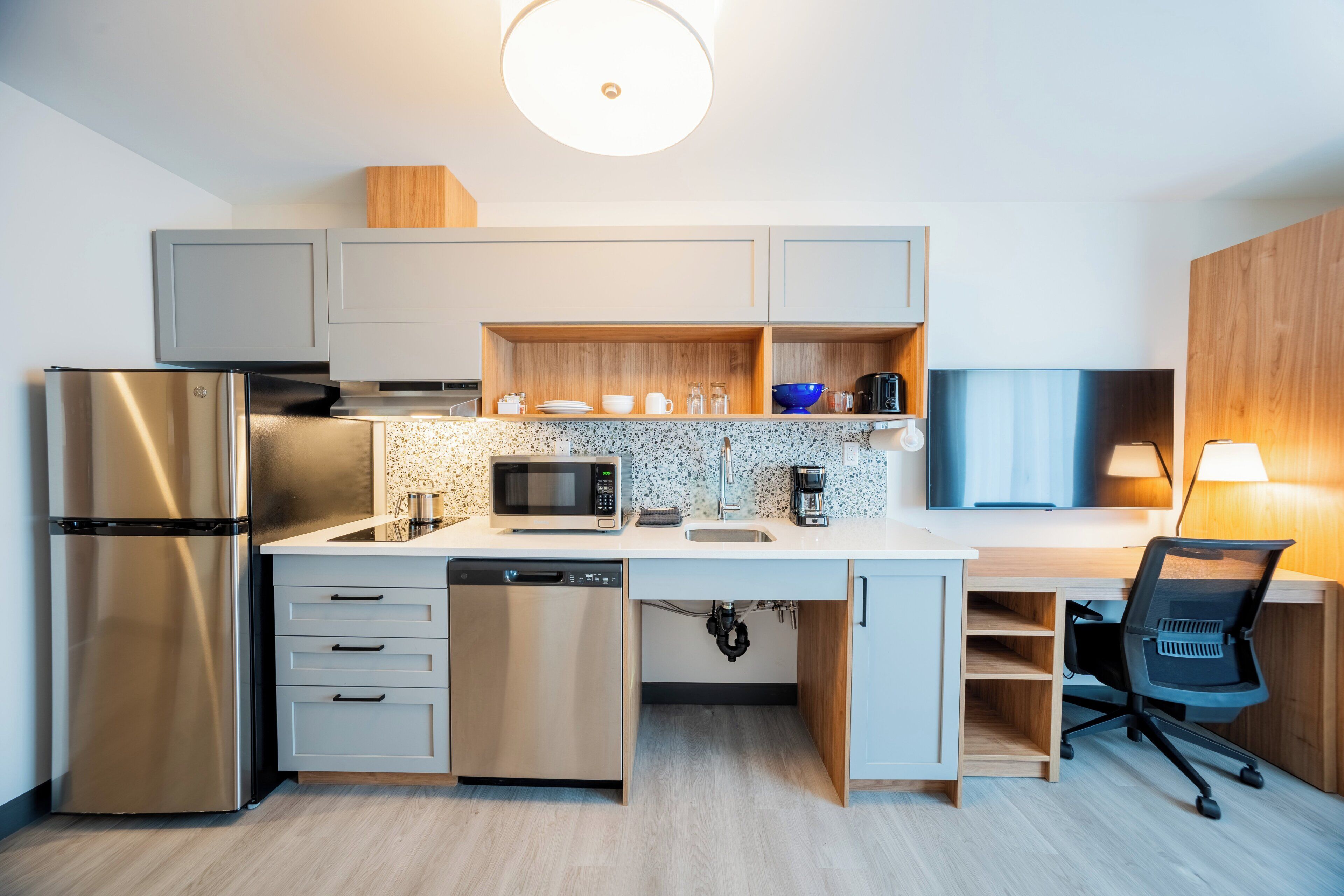 Eine kompakte Küche mit Einbau-Mikrowelle, Edelstahl-Kühlschrank und Geschirrspüler.