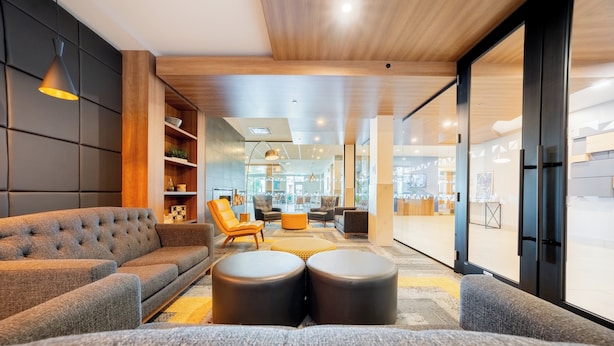 A modern living room with a sofa, ottomans, and a chair.