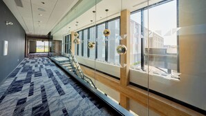 A modern interior with a patterned carpet, glass walls, and a staircase.