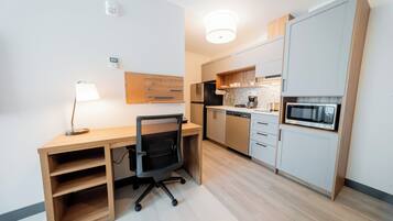 Una cocina compacta con microondas integrado, cafetera y un refrigerador pequeño.