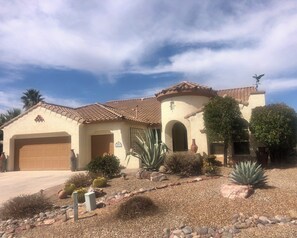 A house with a garage, a well-maintained garden with cacti and shrubs, and a clear blue sky. - GORGEOUS Green Valley AZ house & pool in QC GolfResortSUMMER MONTHLY RENTAL ONLY (Green Valley)