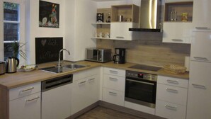 A modern kitchen with white cabinets, stainless steel appliances, and wooden beams on the ceiling.