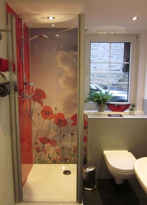 A bathroom with a glass shower enclosure, a toilet, and a window with a view of the outside. - Majestic Apartment in Olsberg (Olsberg)