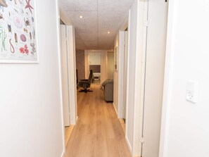 A hallway with wooden flooring, white walls, and a framed picture of marine life.
