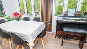 A dining area with a table, chairs, a piano, and a potted plant. - 6 Person Holiday Home in Struer (Struer)