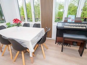 A dining area with a table, chairs, a piano, and a potted plant. - 6 Person Holiday Home in Struer (Struer)