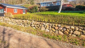 Une propriété rurale avec un mur en pierre, une maison rouge et un bâtiment moderne doté de grandes fenêtres.