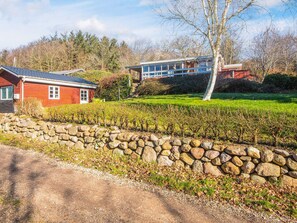 Une propriété rurale avec un mur en pierre, une maison rouge et un bâtiment moderne doté de grandes fenêtres.