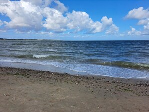 Una playa con olas, piedras y cielo despejado.