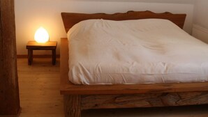A wooden bed with a headboard, a bedside table with a lamp, and a radiator under the bed. - Quellenhof Comfortable Holiday Residence (Retschow)