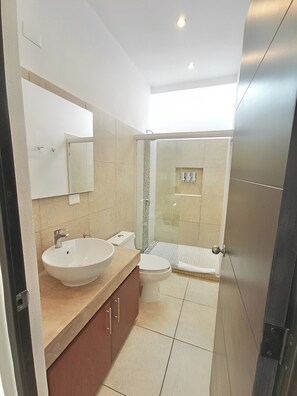 Un baño moderno con un lavamanos grande, inodoro y zona de ducha.