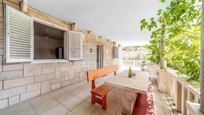 A patio with a wooden bench and table, stone walls, and a view of greenery. - Nice home in Zrnovo with house sea view (Zrnovo)
