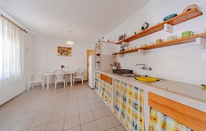 Een koelkast, een oven, een kookplaat, kookgerei, borden en bestek