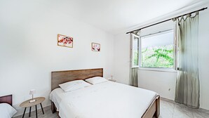 A bedroom with a wooden bed, a small bedside table, a lamp, and two framed floral pictures on the wall. - Nice home in Zrnovo with house sea view (Zrnovo)