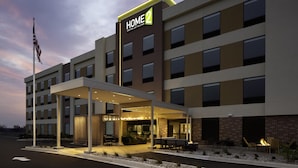 Un hôtel doté d’une entrée abritée, d’un espace extérieur aménagé pour s’asseoir et d’une enseigne indiquant « HOME 2 ».