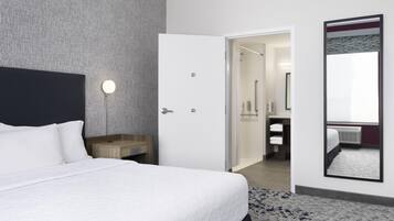 Une chambre d’hôtel comprenant un lit, une table de chevet, un miroir et une porte donnant accès à une salle de bain.