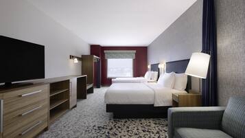 A hotel room with a bed, a TV, a desk, a chair, and a window.
