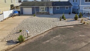 Una casa con garage, vialetto e un’area ghiaiata con piccole piante.
