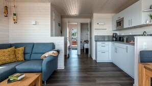 A modern kitchen with white cabinets, a microwave, and a coffee maker. - Houseboat Harmony (Stralsund)